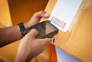 Worker holding barcode scanner scanning red laser on parcel box. Computer tools for warehouse inventory management.