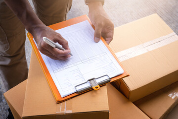 Warehouse worker writing paper on clipboard. inventory management of product. packaging boxes. checking stock. parcel shipment boxes.