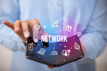 Businessman holding a foldable smartphone with NETWORK inscription, social media concept