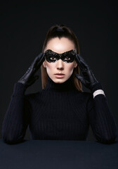 Elegant brunette woman in turtleneck sweater and sequins mask