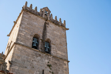 Fototapeta na wymiar Church tower with bells. Exterior of Nossa Senhora da Oliveira Church. Old medieval building. Blue sky.