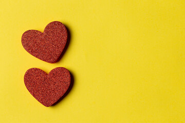 top view of two Red heart-shaped on a yellow paper background