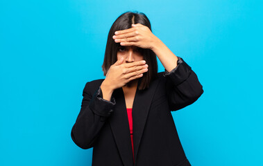 hispanic woman covering face with both hands saying no to the camera! refusing pictures or...