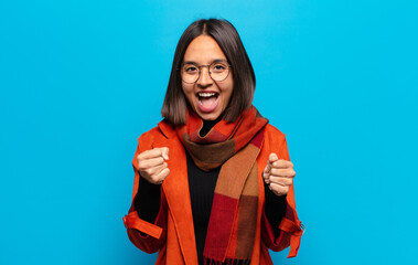 hispanic woman feeling shocked, excited and happy, laughing and celebrating success, saying wow!