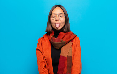 hispanic woman with cheerful, carefree, rebellious attitude, joking and sticking tongue out, having...