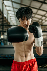 Portrait of professional male boxer make a hitting motion against boxing training ground background