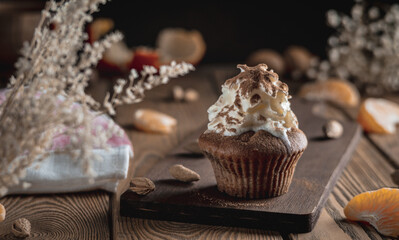 Appetizing fresh cupcake decorated with whipped cream and cocoa powder on a wooden rustic table