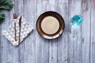 cutlery and empty plate on wooden background top down