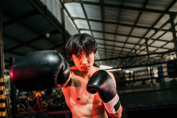 Strong and muscular young man in boxing gear make a hitting motion with the copyspace beside it at...