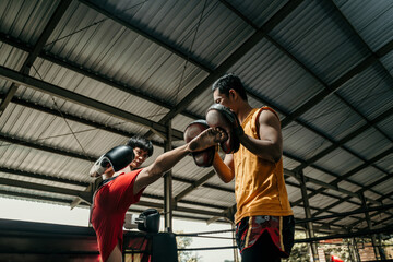 Fototapeta na wymiar boxer and his coach doing some sparring in ring. Boxer and his coach practicing some moves