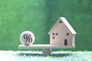 Interest rate up and Banking concept, Model house with Percentage symbol icon on wood scale seesaw on natural green background, Fixed Rate