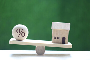 Interest rate up and Banking concept, Model house with Floating rate on wood scale seesaw on...