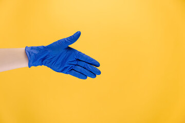 Welcome gesture. Open palm. Close up of unrecognizable male hand in protective blue gloves, isolated on yellow background with copy space for advertisement. Advertising background. Covid-19 concept