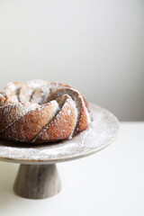 Homemade bundt cake with powder sugar on a white table.