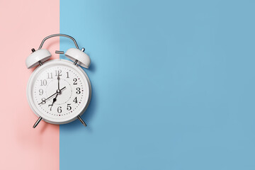 Flat lay white clock alarm in vintage style on blue pink background with copy space
