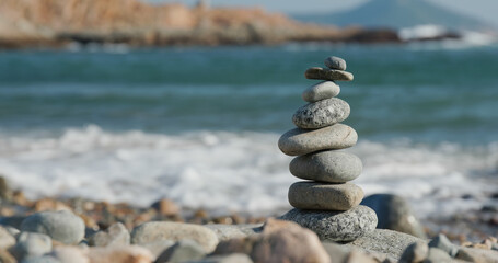 Balanced pebble pyramid on the beach at sunset
