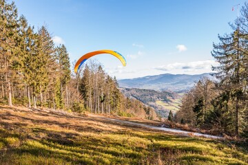 Fliegender Hobby Gleitschirm Flieger an einem Berghang mit professioneller Ausrüstung im Herbst...