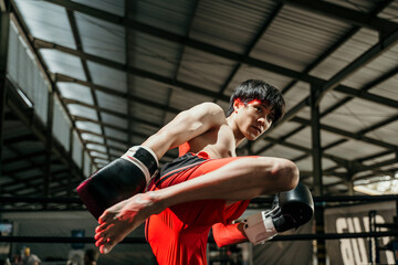 Muscular male fighter in boxing gloves makes knee kick on the boxing ring against boxing match