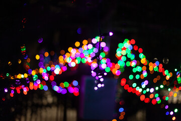 Bright threads of multi-colored garlands in the blur on the branches of the Christmas tree
