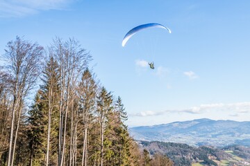 Fliegender Hobby Gleitschirm Flieger an einem Berghang mit professioneller Ausrüstung im Herbst mit Aussicht auf Berge und Alpen im Hintergrund, Deutschland