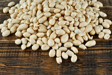 Peeled peanuts on a brown board. Texture of nuts on a wooden old table. Lots of nuts in a pile.