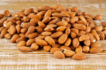 Almonds on a pink scratched board. Texture of nuts on a wooden old table. Lots of nuts in a pile.