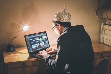 Conspiracy theory concept: young man with aluminum cap searching the internet, sitting lonely in...