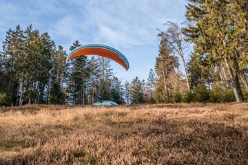Startender Hobby Gleitschirm Flieger an einem Berghang mit professioneller Ausrüstung im Herbst,...