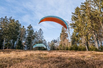 Startender Hobby Gleitschirm Flieger an einem Berghang mit professioneller Ausrüstung im Herbst, Deutschland