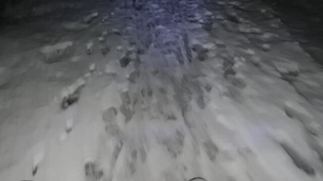 Cyclist Riding the Mountain Bike on the snowy Trail at Night. Extreme Sport and Enduro Biking Concept. Snowy and slippery road covered by few centimetres of sticky snow