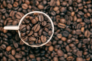 coffee beans close up and a cup full of coffee beans, top view