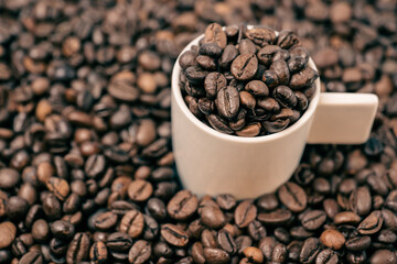 coffee beans close up and a cup full of coffee beans