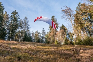 Startender Hobby Gleitschirm Flieger an einem Berghang mit professioneller Ausrüstung im Herbst,...