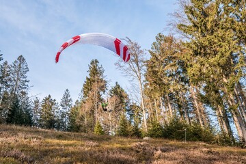 Startender Hobby Gleitschirm Flieger an einem Berghang mit professioneller Ausrüstung im Herbst,...