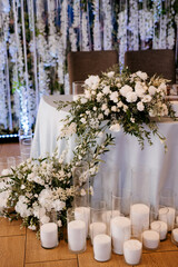 The presidium of the newlyweds in the banquet hall of the restaurant is decorated with candles and green plants