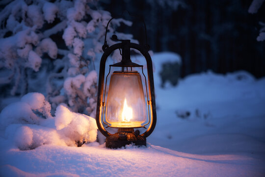 Burning vintage lantern in winter night forest. Beautiful winter background.
