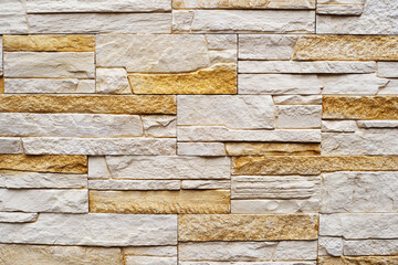 Fragment of a wall made of decorative bricks. The texture of the stone facing panel. Warm tone. Flat frame