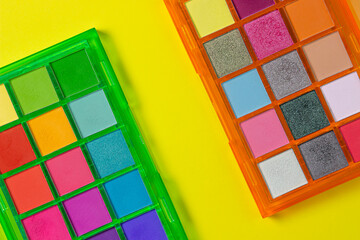 A palette of bright cosmetics. Cosmetics on a yellow background. Bright eye shadow.