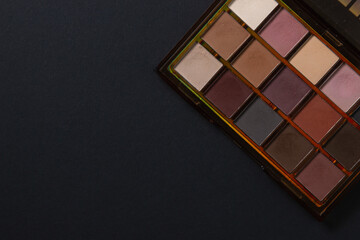 A palette of cosmetics. Cosmetics on a black background. Warm eye shadow.