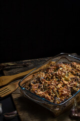 Baked chicken on a black background. Baked chicken with mushrooms and cheese. Food in glassware