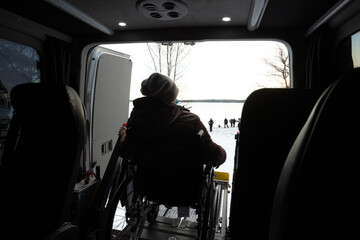 A woman in a wheelchair with her back, she is ready to be unloaded from a wheelchair. Coronavirus protection concept