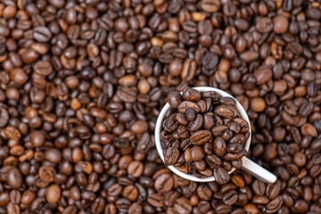 coffee beans close up and a cup full of coffee beans, top view