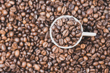 coffee beans close up and a cup full of coffee beans, top view