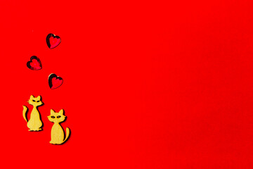 Fototapeta premium Two enamored animals, wooden cats with a crystal heart on a red background. Copy space. Valentine's Day and wedding concept