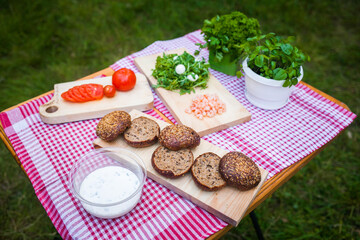 ingredients for cooking vegetarian burgers in nature. The table with the checkered tablecloth in the Park