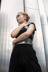 Serious blond woman in black clothes metal panels behind