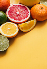 Fresh citrus fruit on yellow table with copy space