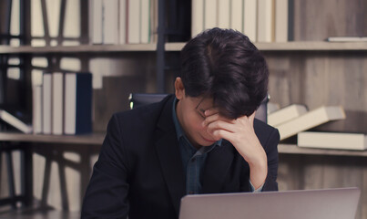 Obraz premium Stressed businessman feeling tired while sitting at his working place in the office, tired or stressed business concept.