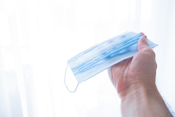 
hand holds a medical face mask against viruses and bacteria on a white background. Pandemic Covid-19. medicine and quarantine concept
