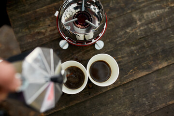 Traveler man pouring fresh hot coffee from geyser coffee maker into cup outdoor